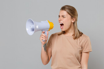 Displeased young blonde woman girl in casual beige t-shirt posing isolated on gray wall background...
