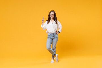 Fototapeta na wymiar Excited young brunette business woman in white shirt glasses isolated on yellow background. Achievement career wealth business concept. Mock up copy space. Holding index finger up with great new idea.