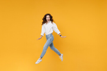 Fototapeta na wymiar Excited young brunette business woman in white shirt posing isolated on yellow background in studio. Achievement career wealth business concept. Mock up copy space. Jumping, spreading hands and legs.