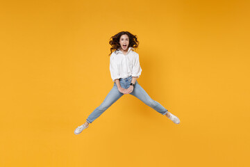 Fototapeta na wymiar Excited young brunette business woman in white shirt posing isolated on yellow wall background studio portrait. Achievement career wealth business concept. Mock up copy space. Jumping, spreading legs.