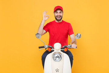 Delivery man in red cap t-shirt uniform driving moped motorbike scooter isolated on yellow background studio Guy employee working courier Service quarantine pandemic coronavirus virus covid-19 concept © ViDi Studio