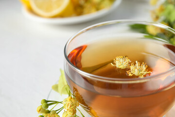 Cup of tea with linden blossom on table, closeup