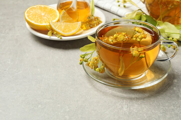 Cup of tea with linden blossom on light grey table, Space for text