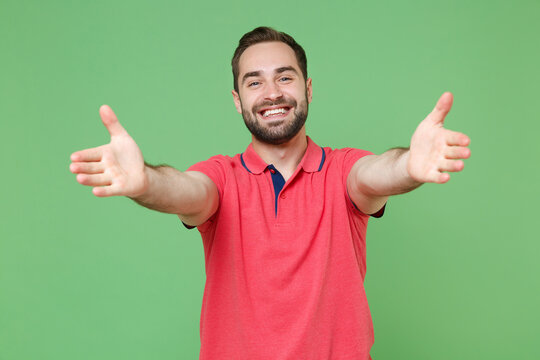 Smiling young bearded man guy in casual red pink t-shirt posing isolated on green background studio portrait. People lifestyle concept. Mock up copy space. Standing with outstretched hands for hugs. - Powered by Adobe