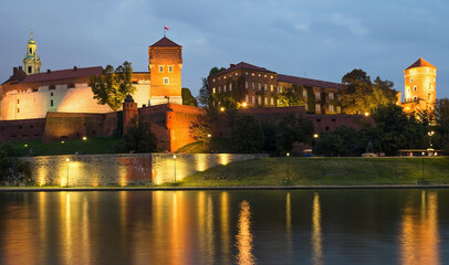 Wawel Castle lit up at night viewed from across the River Vistula.