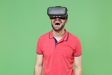 Screaming young bearded man guy in casual red pink t-shirt posing isolated on green wall background studio portrait. People sincere emotions lifestyle concept. Mock up copy space. Watching in headset.