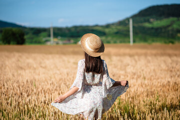 Portrait of a girl from the back in a wheat field. Portrait of a beautiful girl in a white dress...