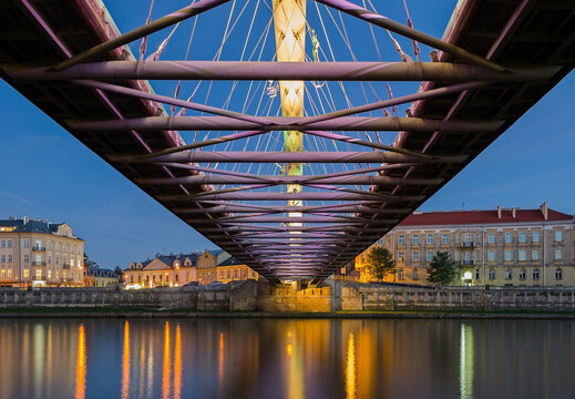 Below the Father Bernatek Footbridge in Krakow, Poland at night.