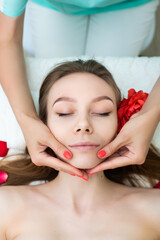 Obraz na płótnie Canvas Young attractive woman gets massage, spa treatment on white towel, rose petals