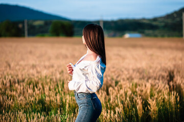 Fototapeta premium Portrait of a girl in a wheat field. Girl in a shirt on a wheat field. Portrait of a beautiful girl in a shirt on a wheat field. Girl in a shirt. Wheat field.