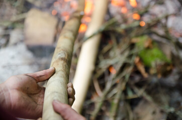 Close up hands and wood of flames on charred wood, in a nature