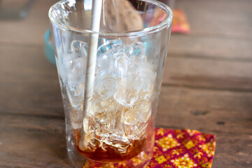Empty Thai style ice americano coffee with recycled straw, Thai pattern textile and purple flower