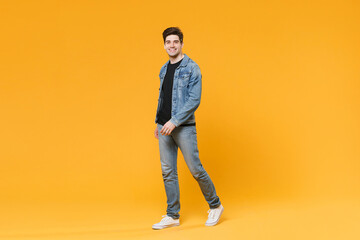 Fototapeta na wymiar Smiling handsome young man guy wearing casual denim clothes posing isolated on yellow wall background studio portrait. People sincere emotions lifestyle concept. Mock up copy space. Looking camera.