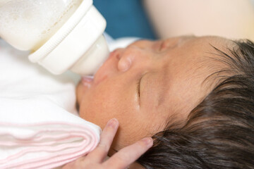 Fototapeta na wymiar 哺乳瓶からミルクを飲む生後1週間の新生児