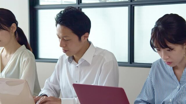 並んでPC作業する人々　ビジネスとチームワーク　スローモーション　パンニング