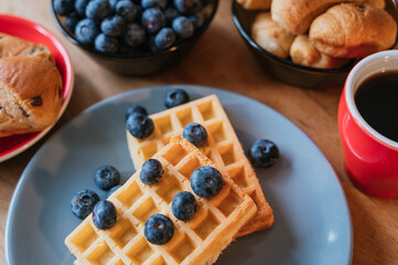 Healthy breakfast of waffles with blackberries, coffee and croissant