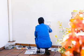Painter working on painting the white wall of the house's terrace. Concept of painting and...