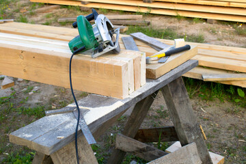 On the boards lies a tool kit. Electric circular saw. Ruler. Hammer.