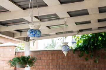 Turkish traditional oriental blue mosaic galss lantern lamp hanged on wooden roof of pergola patio...