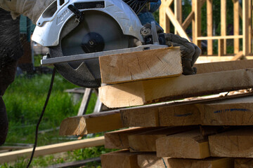 close-up of sawing a board with an electric circular saw.