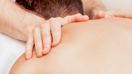 Fototapeta na wymiar Young man receiving back massage by hands of masseur in spa beauty salon.