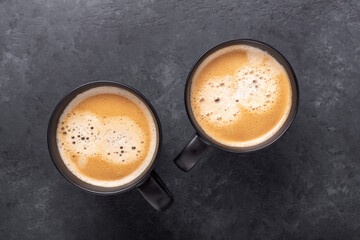 Two cups with coffee on dark stone background. Top view. Copy space