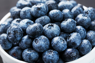 Blueberries in a white Cup on a black textured background.