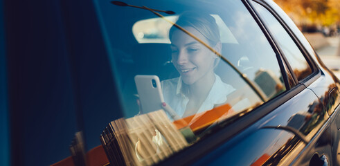 Positive woman expert testing new smartphone application for online communication sending sms with funny content connected to 4g for browsing app, happy female lawyer chatting on website in car