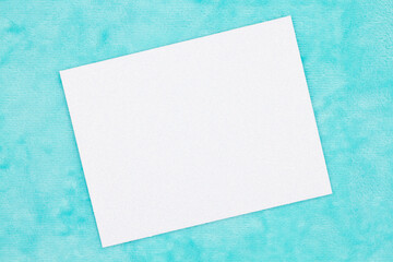 Blank white greeting card on teal plush material mockup