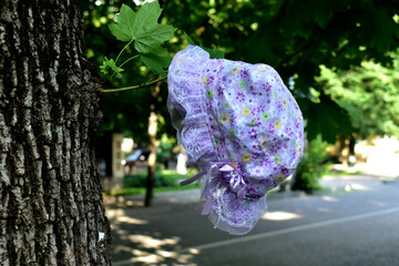 A lost baby hat hanging on a tree branch in the park.