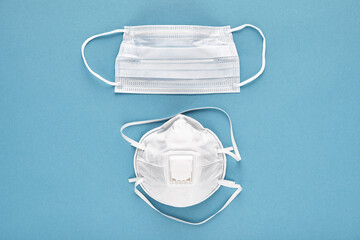 Close-up of medical reusable respirator and disposable face mask on blue background, top view. Concept prevention of respiratory diseases and pneumonia due to new coronavirus.
