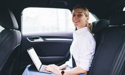 Portrait of happy hipster girl in casual apparel looking at camera and smiling during online blogging via portable pc, cheerful Caucasian woman holding digital tablet while getting to destination