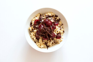 Bowl with oatmeal with cherry and chocolate isolated on white background.