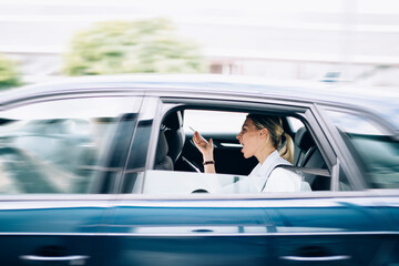 Fototapeta na wymiar Side view of Caucasian female director screaming to male driver during automobile trip for getting to business meeting in downtown, angry woman with hand up feeling fury during car altercate