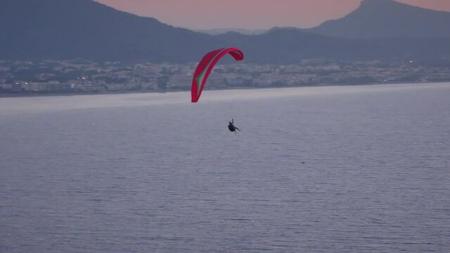 A man on a paraglider on the background of the sea and the city on the shore.