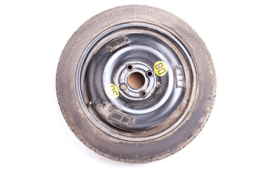 Full size spare tire of a black car isolated on white background in photo studio. Spare summer tire for sale or seasonal replacement in an auto parsing workshop.