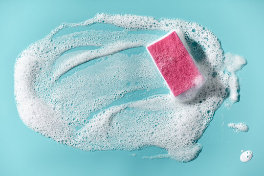 Cleaning sponge and a soapy foam on a blue background. Cleaning concept, cleaning service