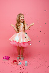 happy Little girl catches confetti on pink background, holiday concept