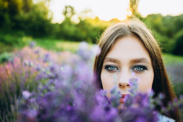 Portrait of a young girl with a bouquet of lavender. Closeup portrait of a happy woman on nature. Soft focus.