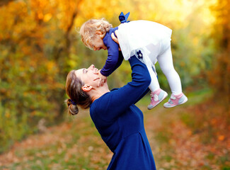 Happy young mother having fun cute toddler daughter, family portrait together. Woman with beautiful...