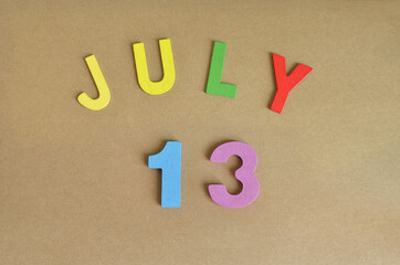 July 13, Toy alphabet with a brown background.