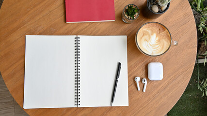 Top view of blank notebooks, earphones and coffee cup on wooden table in home office.