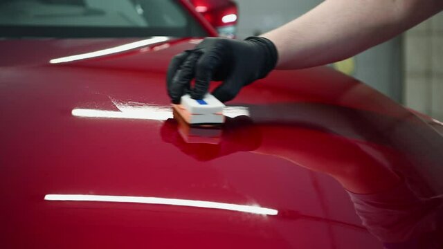 Man worker of car detailing studio applying ceramic coating on car paint with sponge applicator