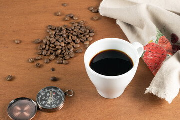 The way of coffee, compass, cup of coffee and coffee beans