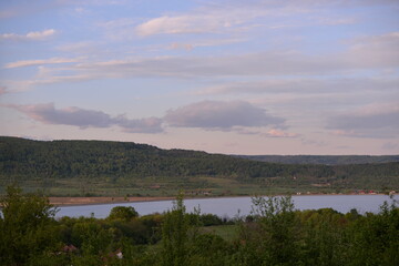 landscape with forest and lake. houses located near a field ready for cultivation