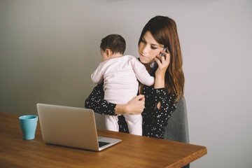 Caucasian mama talking on the phone holding her baby