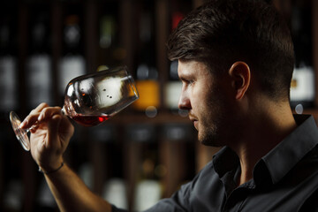 Bokal of red wine on background, male sommelier appreciating drink