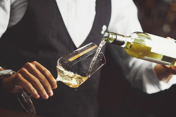 Close up photo, sommelier pouring white wine into wineglasses. - obrazy, fototapety, plakaty