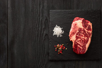 Fresh raw meat with pepper on black slate, on dark background, steak Ribeye
