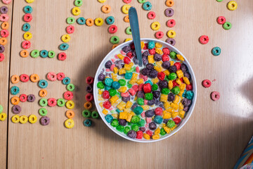 Woman pours cereal, milk into bowl. Bowl of colorful cereal on a table